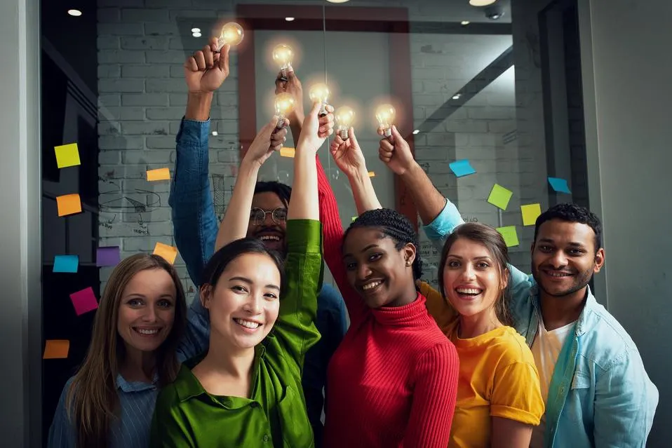 Group Of People Holding Light Bulb Above Head Colorful Shirts